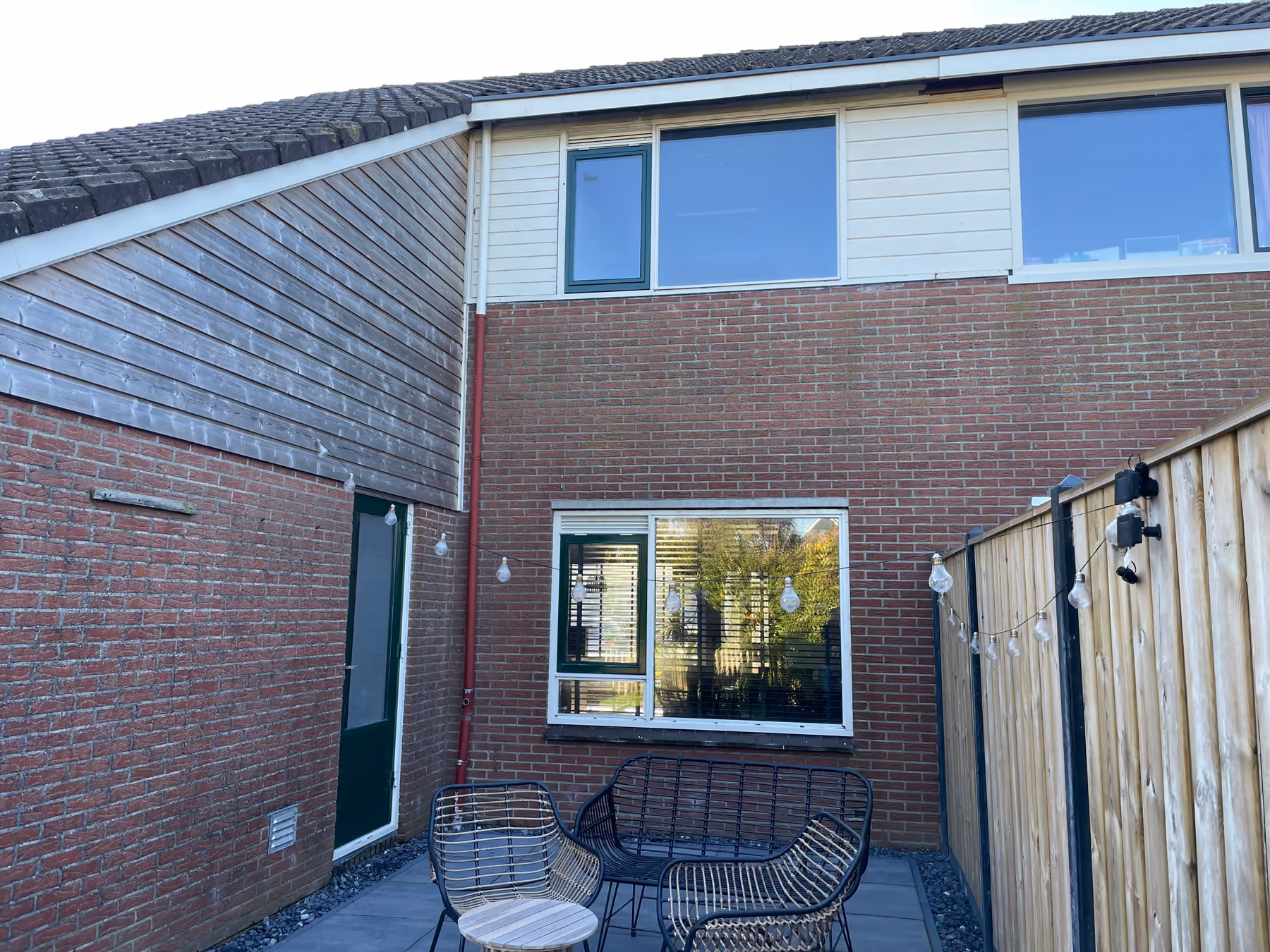 Achtergevel met nieuwe donkergroene kozijnen en terras